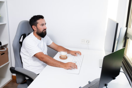 Young caucasian male working at desk with coffee in modern officeの写真素材