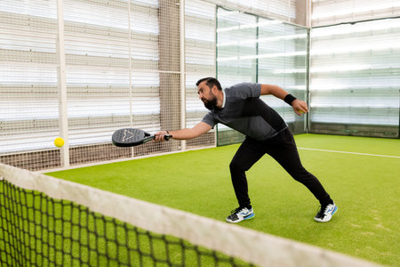 Hispanic male adult playing paddle tennis indoors on courtの写真素材