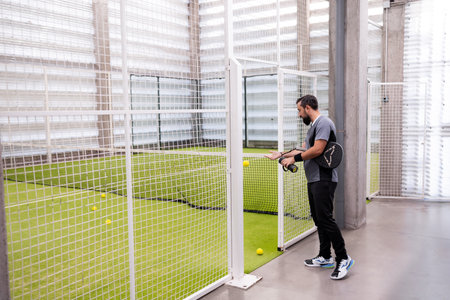 Male engaged in indoor tennis game on artificial grass courtの写真素材