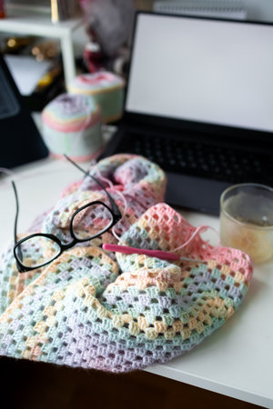 Crochet project with glasses and laptop on workspace desk