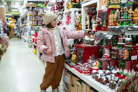Young hispanic girl shopping for Christmas decorations in store aisleの写真素材