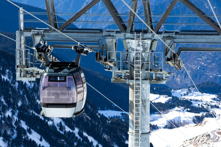 Mountain cable car against snowy alpine backdrop in bright winter day