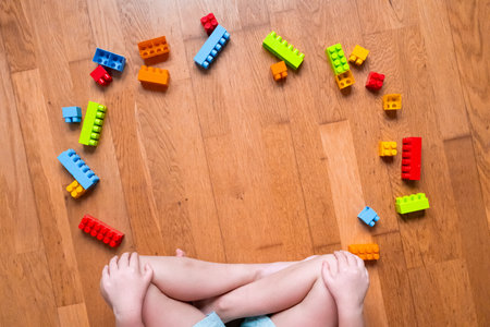 Child playing with colorful building blocks on wooden floor