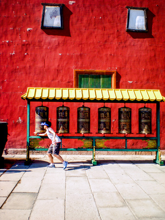 little boy turning the wheel at a buddhist temple ( Putuo Zongcheng)のeditorial素材