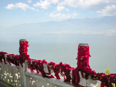 Temple balustrade with red wishing ribbons, overlooking Erhai Lake in Dali, China.の写真素材