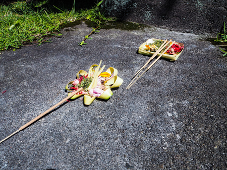 Three Balinese offerings with incense sticks on a paved pathway, Amed, Bali, Indonesia
