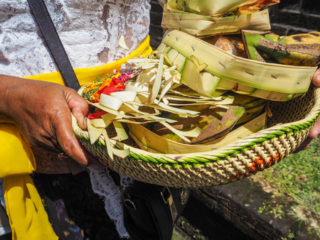 Asian woman holding a basket filled with offerings in her hands, Besakih temple, Bali, Indonesiaの写真素材