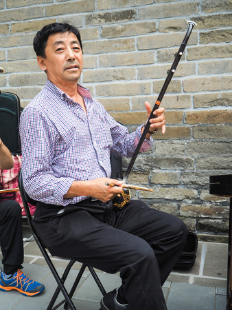 Beijing, China - September 2017: Chinese man playing the Chinese violin called erhu in a small ensemble outdoor at the temple of Heavenのeditorial素材