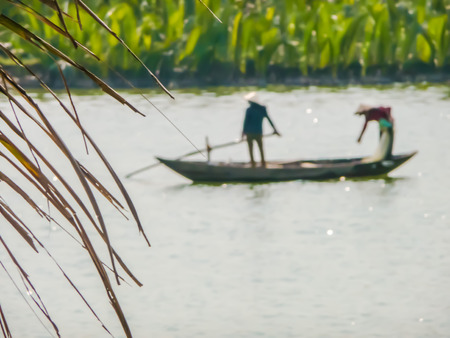 Two men wearing traditional Vietnamese clothing rowing a boat in the Mekong Delta, Vietnam