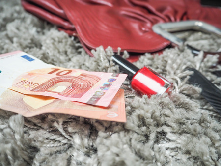 Two ten euro notes lying next to a red female handbagの写真素材