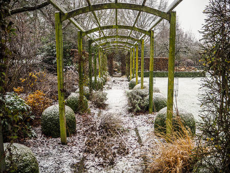 Wooden pergola structure during winter a in snow covered gardenのeditorial素材