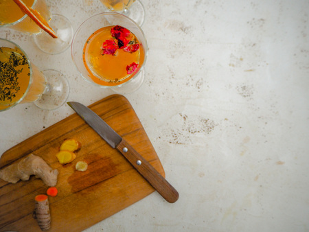 Multiple glasses with a variety of flavored kombucha such as cinnamon, turmeric, ginger, raspberry and a wooden cutting board on a white backgroundの写真素材