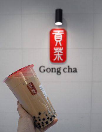 March 2019 - South Korea: Caucasian female hand holding a jumbo size black milk tea with pearls or bubble tea from the Taiwanese brand Gong Chaのeditorial素材