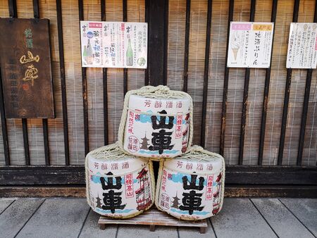 TAKAYAMA, JAPAN - MAY 2019: Three traditional sake barrels outside Harada sake brewery in the old...