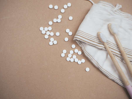 Bamboo toothbrush and dental tabs on a wooden background as a plastic free swap. Zero waste personal care products.の写真素材