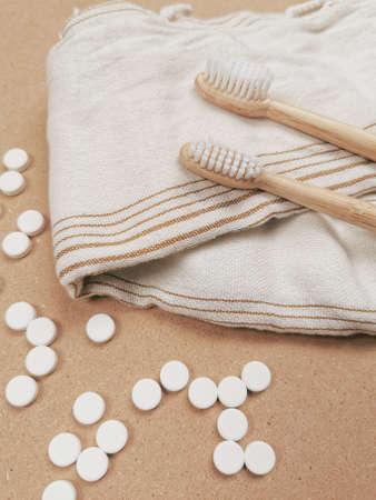 Bamboo toothbrush and dental tabs on a wooden background as a plastic free swap. Zero waste personal care products.の写真素材