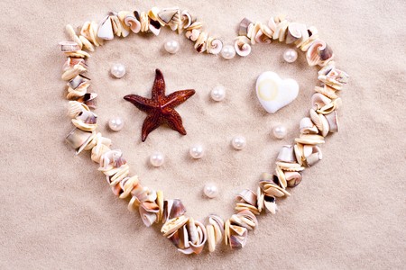 seashells in sand in the form of heartの写真素材
