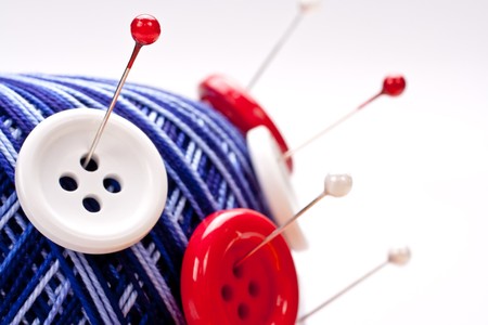 red and white pins in red wool ball with buttons