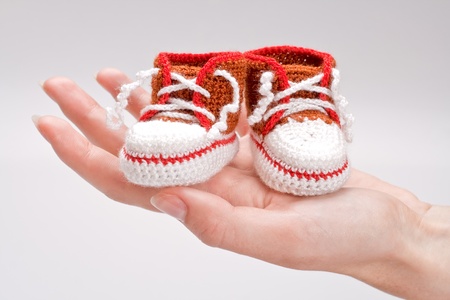 crocheted booties for a boy in the girl's handの写真素材