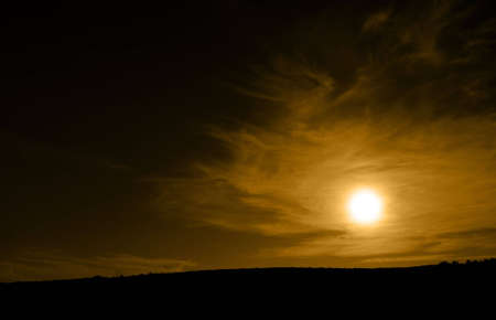 Golden sun over a black horizonの写真素材