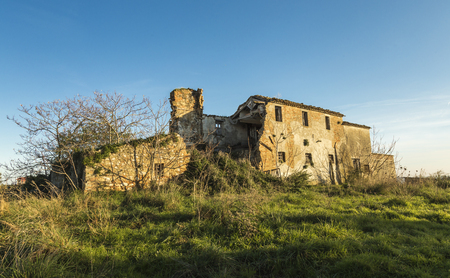 Old abandoned farmhouse in a meadow under blue skyの写真素材