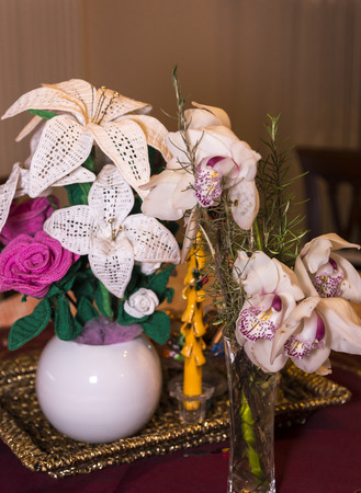 3D white and pink crocheted flowers on natural branch near real orchidsの写真素材