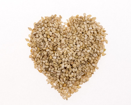 Sesame seeds in the form of heart on white backgroundの写真素材
