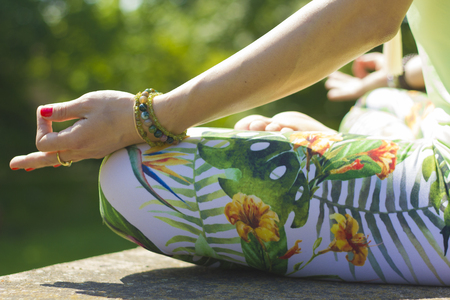 young woman meditating in a lotus position wearing floral clothesの写真素材