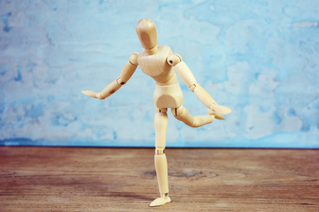 Wooden model showing dramatical pose in front of blue art backgroundの写真素材