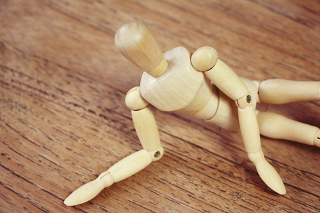 Wooden model showing dramatical pose on darker wooden table backgroundの写真素材