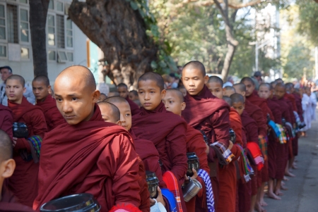 AMARAPURA, MYANMAR - JAN 15 : Buddhist novices walk to collect alms and offerings on January 15, 2013 in Amarapura near Mandalay, Myanmar. This procession is held every day.のeditorial素材