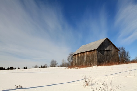 Old abandoned barn in a field on a bright winter morning.の写真素材