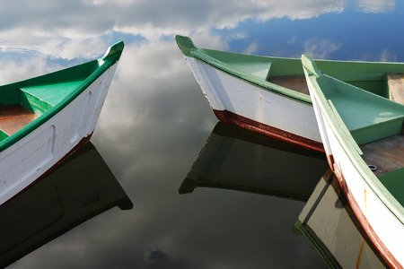 Sky reflection and wooden green boats awaiting tourists at the jettyの写真素材