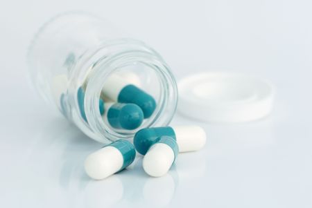 Bottle turned on its side with some capsules tumbling out.