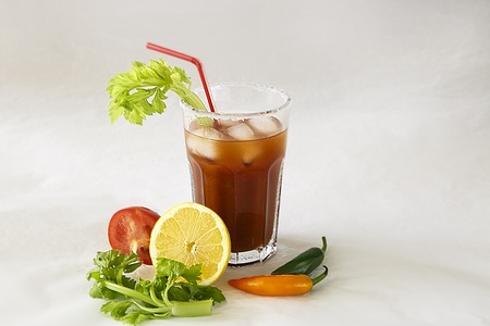 a glass with a cocktail "Bloody Merry" with ice and a sprig of celery on a white background, the top of the glass is decorated with saltの写真素材