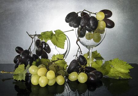 Still life with fresh grapes, green leaves and glassの写真素材