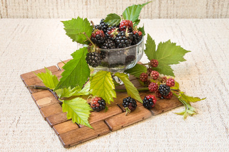 BlackBerry in a glass on the table close-up. blackberries on a wooden background and leaves