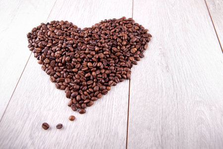Heart of coffee beans on a wooden backgroundの写真素材