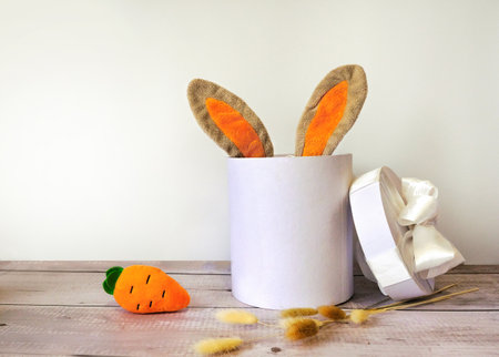 easter rabbit ears in a gift box with carrot on wooden backgroundの写真素材