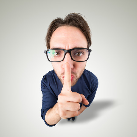 Man say Shhh with hand gesture looking in cameraの写真素材
