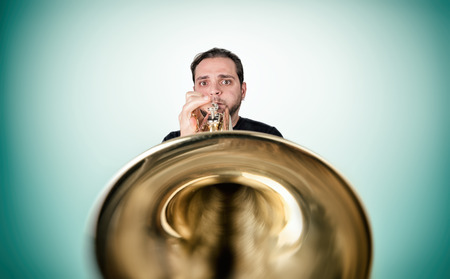 Funny man is playing trumpet looking in cameraの写真素材