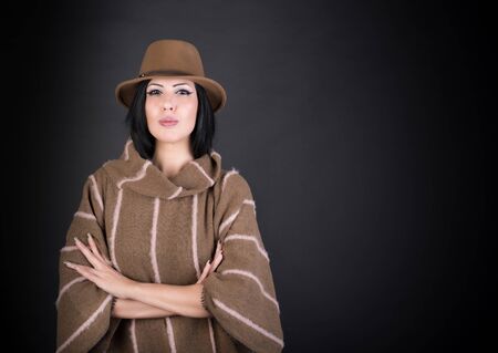 Fashion beautiful woman in country outfit and hat looking in camera on blackの写真素材