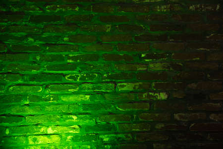 Old brick wall with emerald green neon lighting effect as background texture.の写真素材