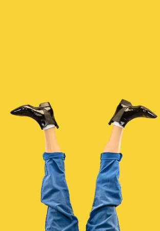 Mans legs in black stylish shoes isolated on yellow background.