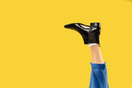 Mans legs in black stylish shoes isolated on yellow background.の写真素材