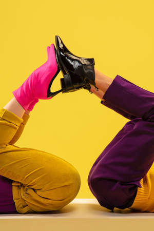 Fashion models feet in bright stylish footwear isolated on yellow background.の写真素材