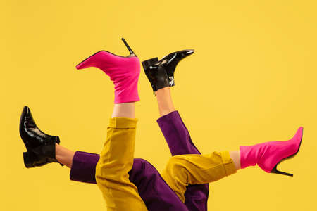 Fashion models feet in bright stylish footwear isolated on yellow background.の写真素材