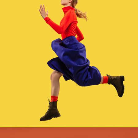 Young female model in bright casual wear isolated on yellow studio background