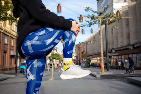 Crop portrait of young sport woman in blue leggings and black sweatshirt doing fitness exercise in...