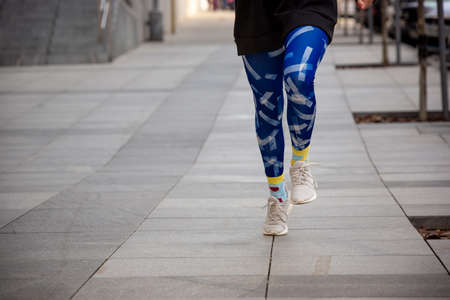 Running. Young happy woman in blue leggings and black sweatshirt doing morning exercise in the city...